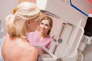  Eine Krankenschwester hilft ein Patient sich in einer Mammographie